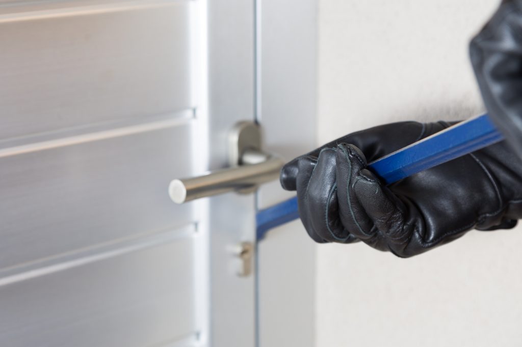 Thief with a bar of iron in the hand to open a door